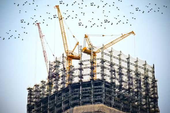 Cranes on top of big building under construction.